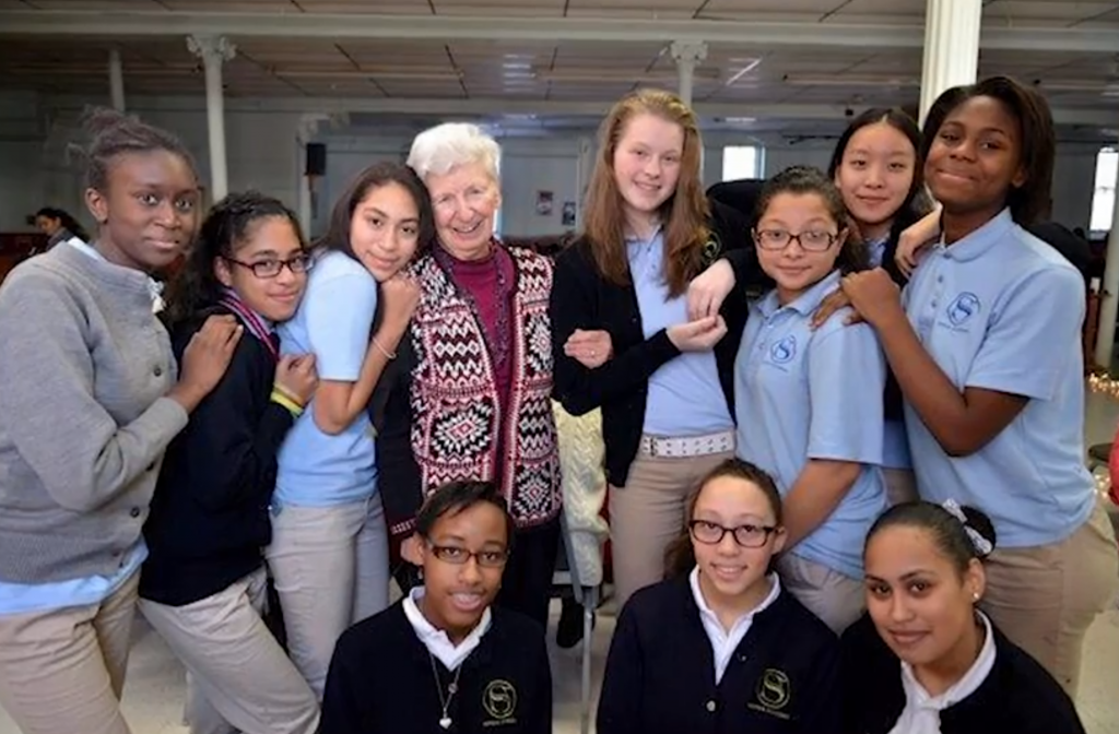 Mutuality, cooperation and supportive relationships infuse Sophia Academy in Providence, Rhode Island, as evidenced by this pre-pandemic photo. As the school’s founder and former head of school, Sister Mary Reilly (center) stays involved. She has helped deliver groceries to students and encourages them in Zoom video meetings. (Sophia Academy photo)