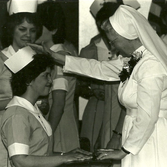 A nursing student receives her cap—and a blessing—from Sister Consuela.